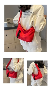 Detail of red nylon crossbody bag with sporty black woven zipper pull and adjustable strap