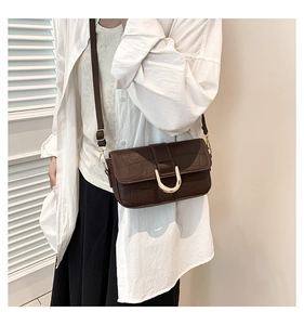 Detail of dark brown crocodile-embossed handbag with gold U-shaped metal lock