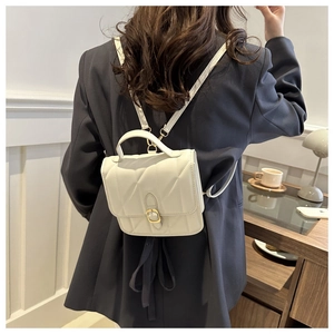 Detail of a cream quilted backpack with golden buckle clasp and elegant faux leather texture
