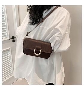 Detail of dark brown crocodile texture shoulder bag with golden U-shaped buckle