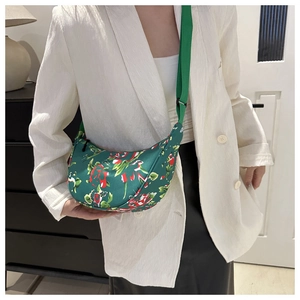 Detail view of crescent crossbody bag with green floral pattern and adjustable strap