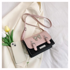 Detail of pink and black bow shoulder bag on white fabric with floral accents