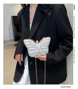 Detail of butterfly evening clutch with sparkling sequins and pearl clasp on model