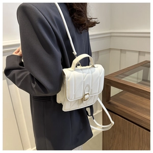 Detail view of a white quilted mini backpack with a vintage gold buckle and fine stitching