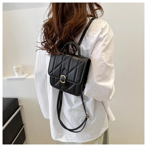Detailed view of the quilted black leather backpack with elegant gold buckle on a model