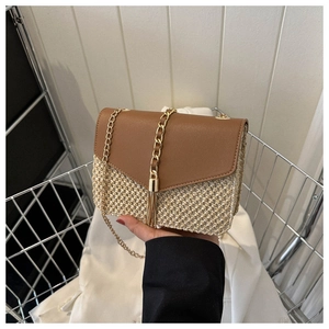 Detail of woven straw bag with brown leather flap and elegant gold fringe chain