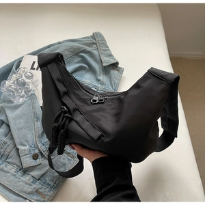 Detail showing black nylon fabric texture and woven rope accents on large hobo bag