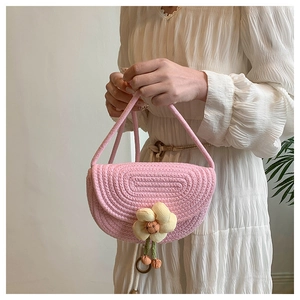Detail of pink hand-woven shell bag featuring a large decorative 3D floral accent
