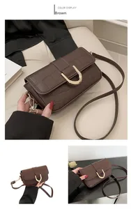 Detail of brown crocodile pattern shoulder bag with a gold horseshoe buckle closure
