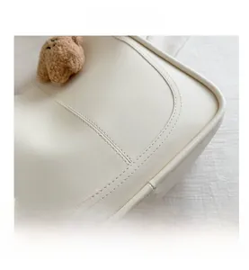 Detail of creamy white leather tote with lychee grain texture and cute bear pendant