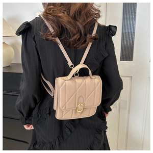 Model wearing a beige quilted leather mini backpack with golden buckle and chain details