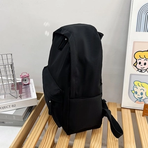 Vue détaillée du sac à dos noir minimaliste avec poche latérale sur un banc en bois
