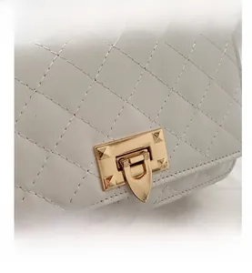 Gros plan du sac bandoulière blanc matelassé avec fermoir rotatif doré et texture cuir