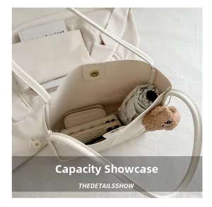 Spacious interior of a cream crossbody tote bag with magnetic closure and bear charm