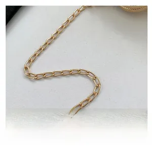 Macro shot of gold metal chain strap featuring polished oval links for women handbags