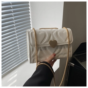 Detalle de bolso bandolera blanco acolchado con corazón y gran hebilla de metal dorado