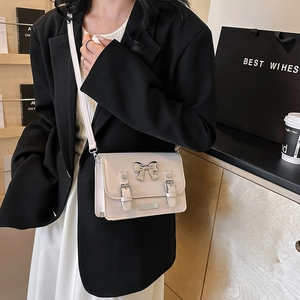 Petit sac bandoulière bicolore chic avec nœud argenté porté sur une veste noire