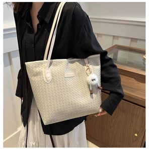 Détail du sac cabas blanc tressé avec breloque en fourrure porté par un mannequin