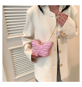 Pink butterfly shaped sequin handbag with gold chain strap held by a model
