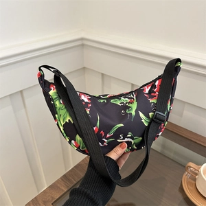 Chic floral crescent crossbody bag with red and green blossoms on black fabric