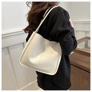 Detailed side view of cream white shoulder tote bag with stitching on female model
