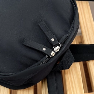 Détail des doubles fermetures éclair en métal et du nylon texturé sur le sac à dos noir
