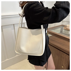 Minimalist beige tote bag featuring slim double shoulder straps and vertical stitching detail