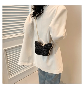 Close-up of butterfly sequin bag with gold chain strap on white blazer outfit