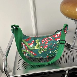 Green crescent crossbody bag with red floral patterns and adjustable green strap