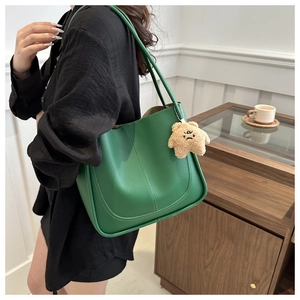 Detail of green leather tote bag with U-shaped stitching and plush star charm accessory
