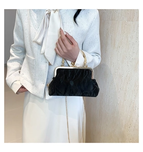 Detail of black pleated clutch with gold metal frame and decorative spherical clasp