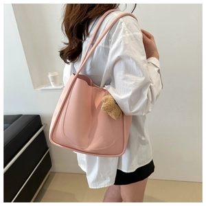 Pink faux leather tote bag with long strap and cute brown plush bear charm detail