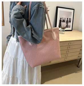 Détail du sac cabas tissé rose clair montrant la texture et la petite étiquette en cuir