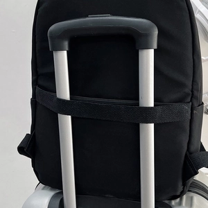 Détail de la sangle pour valise sur un sac à dos noir fixé à une poignée de bagage