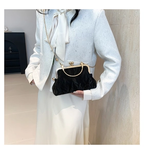 Detail showing elegant black pleated fabric and vintage gold clasp on stylish handbag