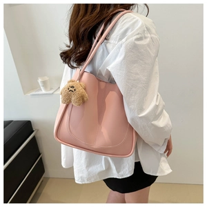 Detailed view of pink shoulder tote bag with a cute brown plush bear charm accessory