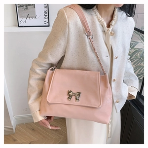 Detailed view of pink shoulder bag with metallic bow buckle and chain strap