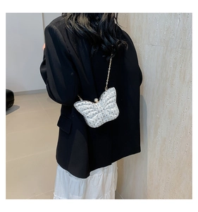 Detailed view of a shiny silver butterfly shaped sequin bag with gold chain strap