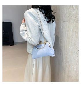 Detail of light blue pleated silk handbag with golden metal clasp and chain strap