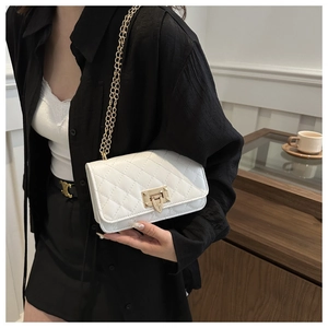 Détail de la texture matelassée blanche avec chaîne dorée et fermoir sur le sac à main
