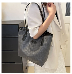 Détail de la texture tissée et de l'écusson en cuir sur un grand sac cabas gris