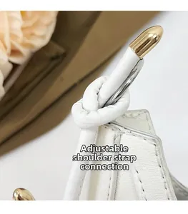 Détail de la bandoulière en cuir réglable avec embouts dorés sur sac à main blanc