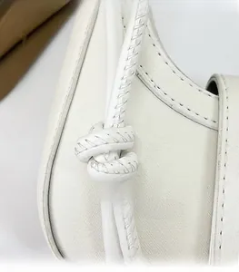 Détail de la poignée de sac en cuir blanc avec nœud décoratif et coutures de précision