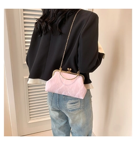 Pink satin handbag with gold frame closure and chain strap worn as a crossbody bag