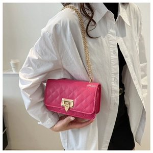 Détail d'un sac bandoulière rose fuchsia matelassé avec chaîne dorée et fermoir