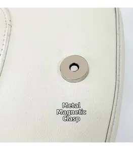 Gros plan du fermoir magnétique argenté sur un sac à bandoulière en cuir blanc