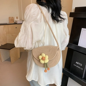 Mini woven shell bag with yellow sunflower accent shown on a model's shoulder