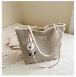 Détail du sac fourre-tout tissé crème avec étiquette en cuir et peluche de monstre