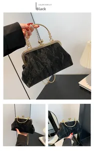 Detail view of the black velvet clasp bag with golden metal handle and fine chain strap