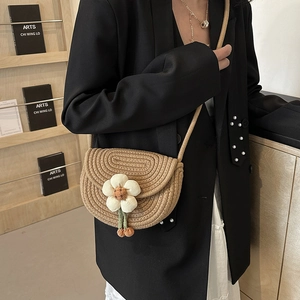 Mini hand-woven shell bag with white flower decoration on a stylish khaki shoulder strap